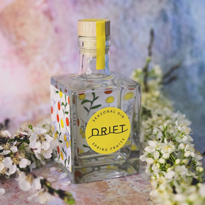 350ml Drift Spring Fruits gin with apricot and plum blossoms surrounding it.